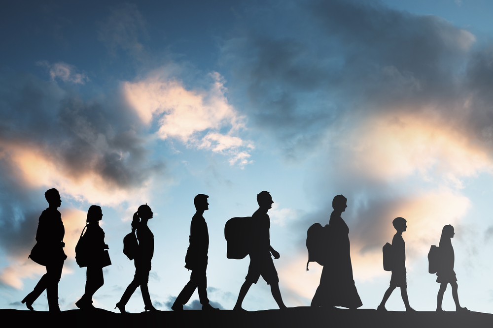 silhouette of refugees people with luggage walking in a row