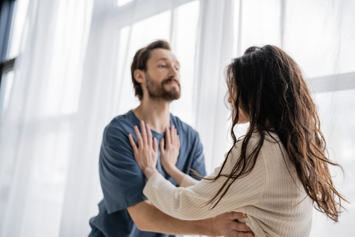 woman pushing blurred aggressive boyfriend during quarrel at home