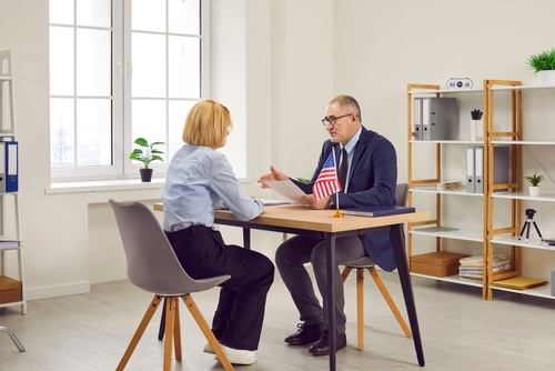 united states of america embassy consul discusses visa application with customer at table in office